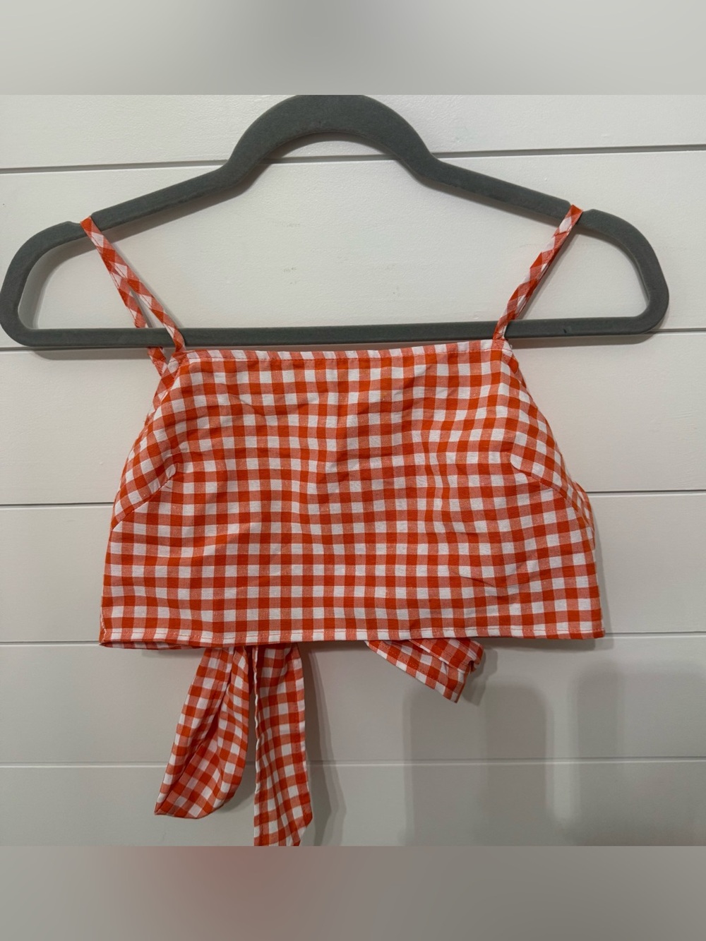 An orange and white gingham crop top with spaghetti straps and a back tie